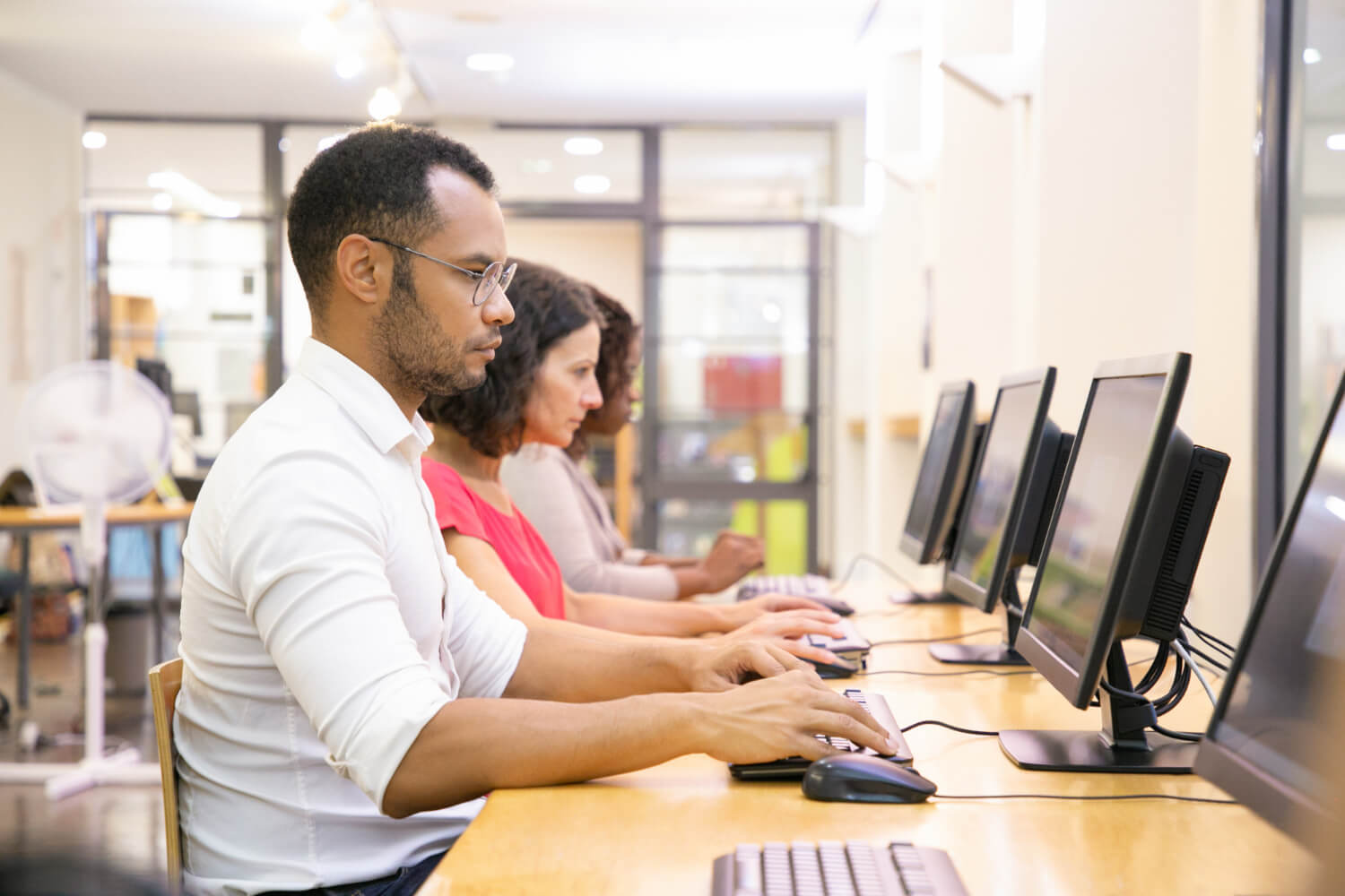 Personas trabajando en computadoras en una oficina iluminada