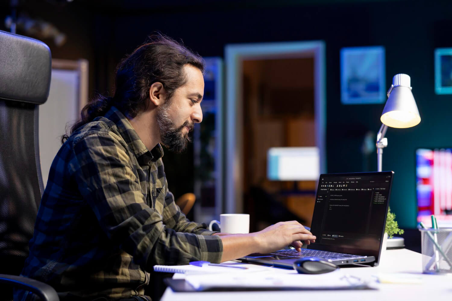 Persona programando en una laptop en una oficina con iluminacion tenue