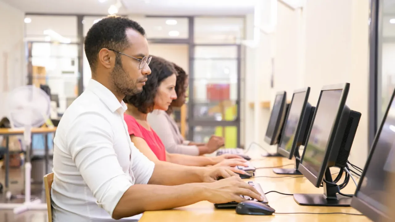 Personas trabajando en computadoras en una oficina iluminada