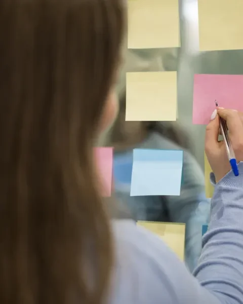 Mujer de espaldas escribiendo en notas post-it