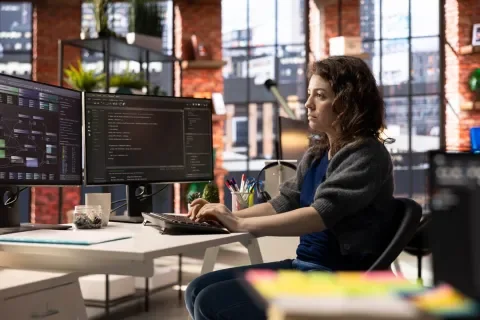 Mujer trabajando frente a dos monitores