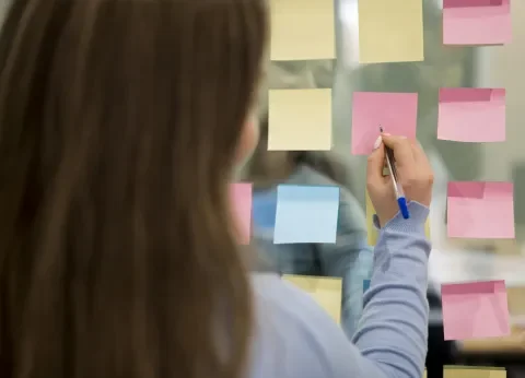 Mujer de espaldas escribiendo en notas post-it