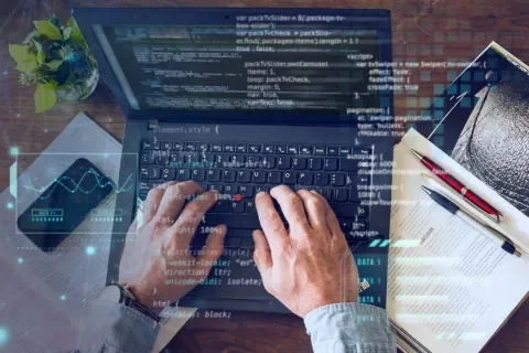 Manos tecleando en una laptop con líneas de código en pantalla