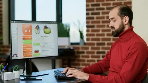 Hombre sentado frente a una pantalla analizando gráficos