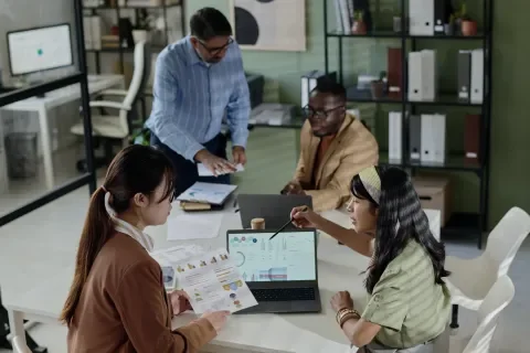 personas trabajando en una sala de juntas analizando datos en computador