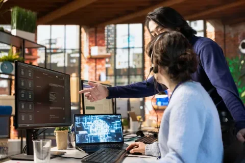 Hombre y mujer trabajan en oficina, mirando una pantalla con gráficos