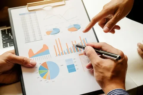 Gráficos y diagramas en una carpeta, manos señalando con un bolígrafo y el dedo