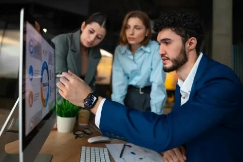 Personas revisando gráficos en una computadora en una oficina