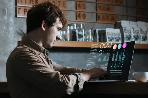 Persona trabajando en laptop con gráficos, en una cafetería
