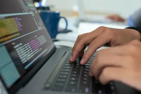 Manos escribiendo código en una computadora portátil
