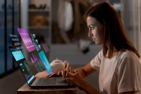 Mujer usando laptop con gráficos holográficos. Ambiente cálido y moderno.